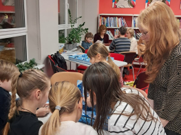 Bērnu un jauniešu grupa telpā pie galda spēlējot galda spēles