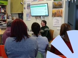 cilvēki no mugurpuses, sēž telpā, priekšā lektors