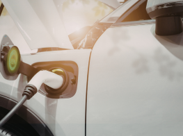 Gaišs automobilis ar elektrouzlādes vadu